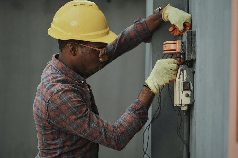electrician troubleshooting an issue wearing safety helmet and gloves